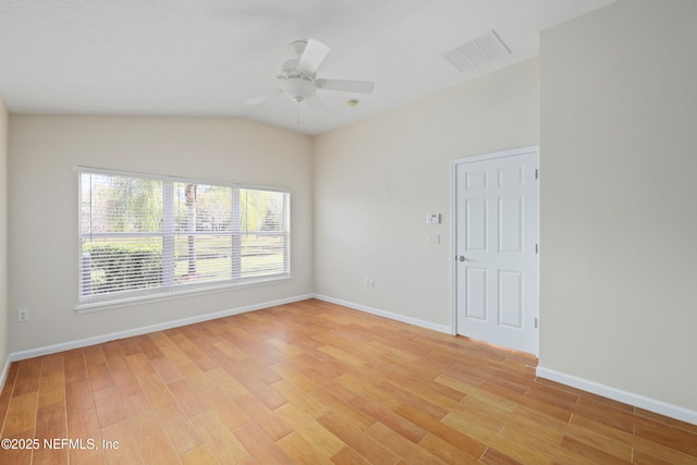 empty room with visible vents, light wood finished floors, baseboards, ceiling fan, and vaulted ceiling