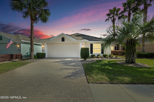 view of front of home with stucco siding, a front lawn, decorative driveway, and a garage