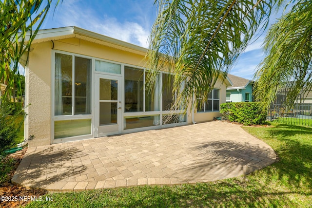 back of house with a patio, fence, a sunroom, stucco siding, and a lawn