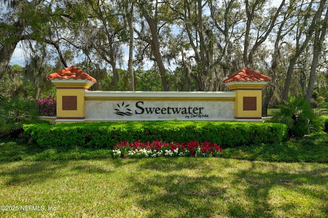 community / neighborhood sign featuring a lawn and fence