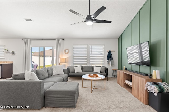 living room with carpet flooring, a ceiling fan, visible vents, and a textured ceiling