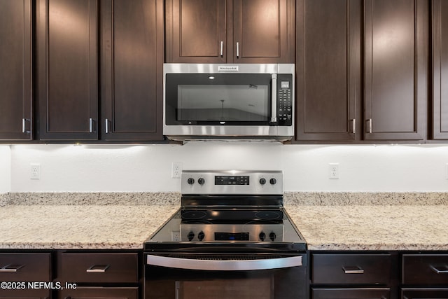 kitchen featuring stainless steel microwave, light stone countertops, electric range, and dark brown cabinets