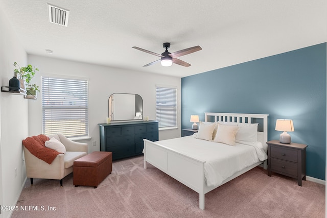 bedroom with visible vents, light carpet, baseboards, and ceiling fan