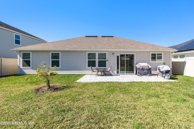 rear view of house featuring a patio, a lawn, and fence