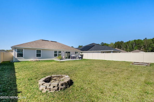 back of house with a lawn, a fenced backyard, and a fire pit