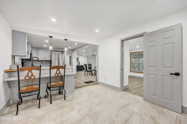 6099 Milligan Rd, Keystone Heights, FL 32656 - kitchen with a breakfast bar area, a peninsula, freestanding refrigerator, gray cabinetry, and pendant lighting
