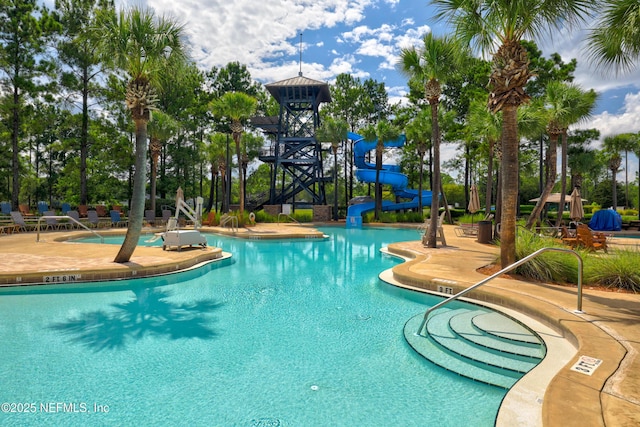 community pool with a patio and a water slide