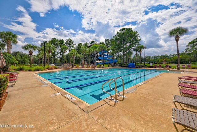 community pool with a patio area and a water slide