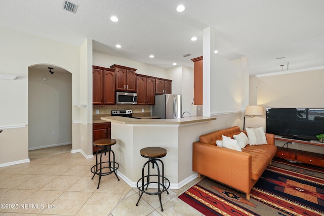 kitchen featuring a kitchen bar, visible vents, appliances with stainless steel finishes, light tile patterned flooring, and open floor plan