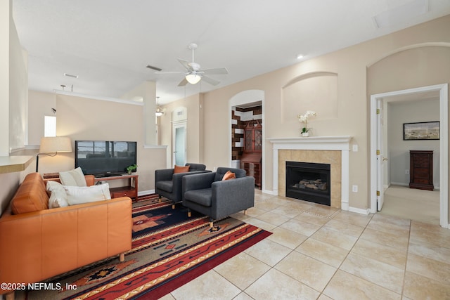 living room with light tile patterned floors, baseboards, visible vents, a tiled fireplace, and a ceiling fan