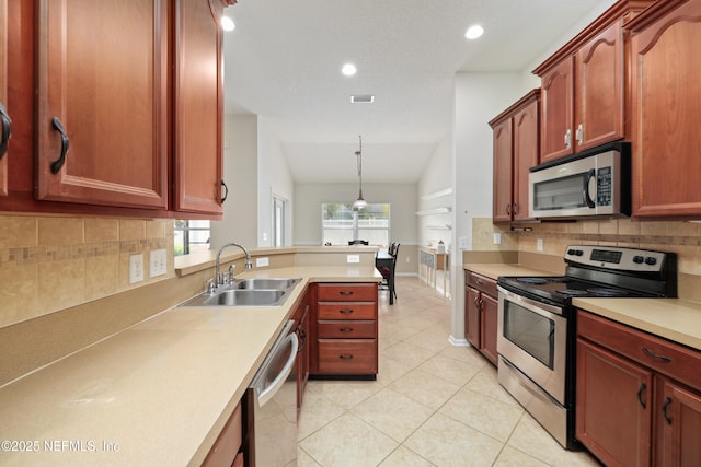 kitchen with light tile patterned floors, vaulted ceiling, light countertops, a sink, and stainless steel appliances