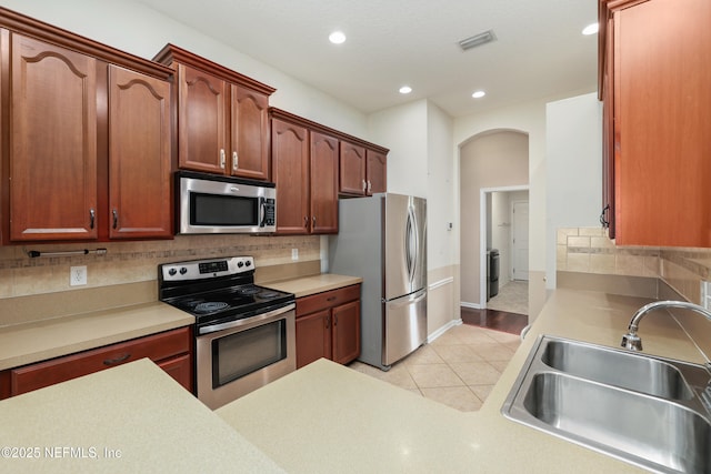 kitchen with light tile patterned floors, arched walkways, visible vents, appliances with stainless steel finishes, and a sink