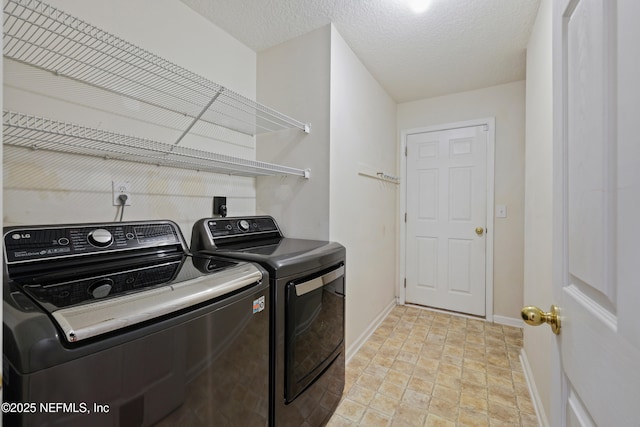 laundry room with laundry area, washing machine and clothes dryer, baseboards, and a textured ceiling