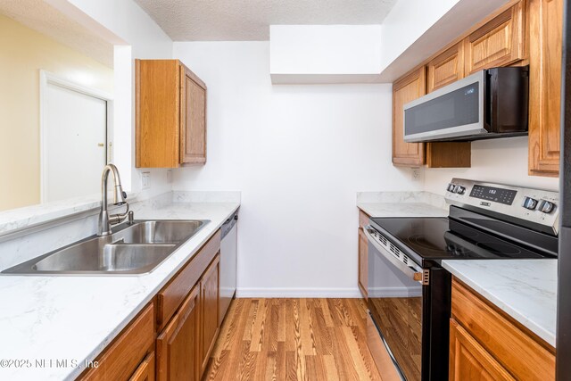8331 Pineverde Ln, Jacksonville, FL 32244 - kitchen with a sink, a textured ceiling, stainless steel appliances, light wood-style floors, and baseboards