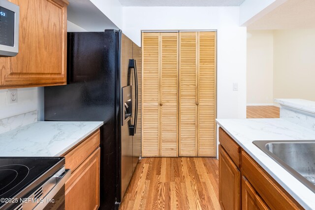 8331 Pineverde Ln, Jacksonville, FL 32244 - kitchen with light stone counters, stainless steel microwave, black fridge with ice dispenser, and light wood-type flooring