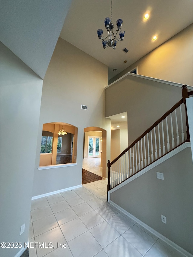 3549 Victoria Lakes Dr W, Jacksonville, FL 32226 - staircase with visible vents, baseboards, a chandelier, a high ceiling, and arched walkways