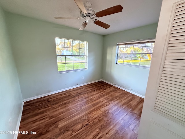 empty room featuring ceiling fan, baseboards, and wood finished floors