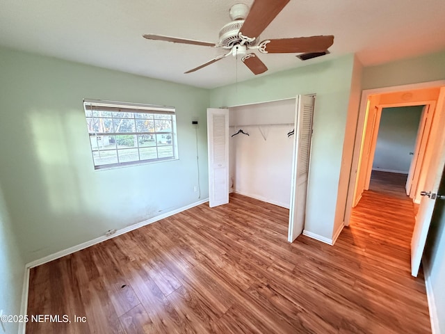 unfurnished bedroom featuring ceiling fan, a closet, baseboards, and wood finished floors