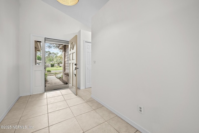 foyer with baseboards, light tile patterned floors, and high vaulted ceiling