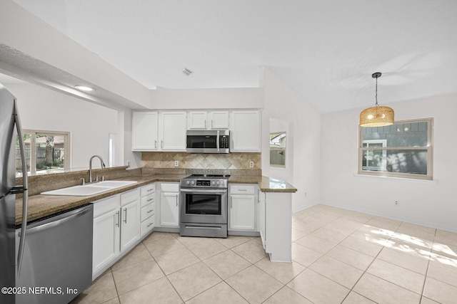 kitchen with decorative backsplash, white cabinetry, a sink, appliances with stainless steel finishes, and light tile patterned floors