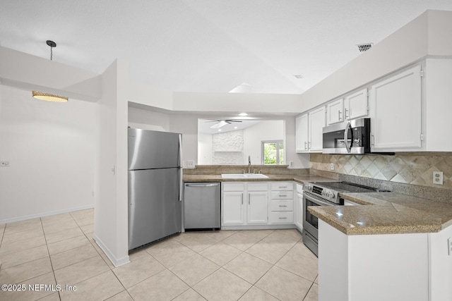 kitchen featuring light tile patterned flooring, appliances with stainless steel finishes, a sink, a peninsula, and decorative backsplash