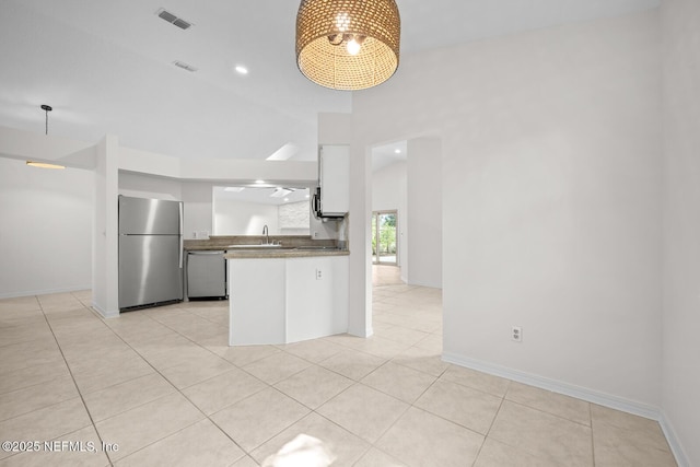 kitchen featuring visible vents, a towering ceiling, white cabinetry, a sink, and stainless steel appliances