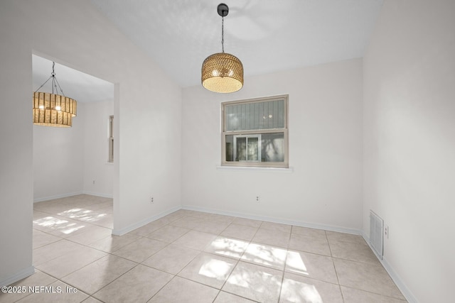 tiled empty room with baseboards, visible vents, vaulted ceiling, and a chandelier