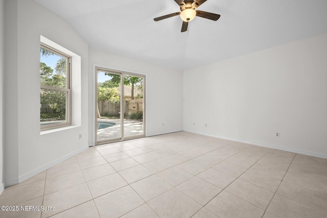 spare room featuring baseboards, ceiling fan, light tile patterned floors, and vaulted ceiling