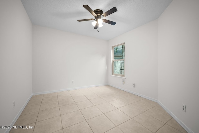 spare room featuring ceiling fan, light tile patterned flooring, and a textured ceiling