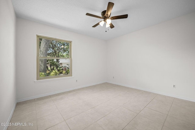 empty room featuring light tile patterned flooring, ceiling fan, and baseboards