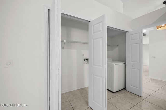 clothes washing area with light tile patterned flooring, laundry area, washer / dryer, and baseboards