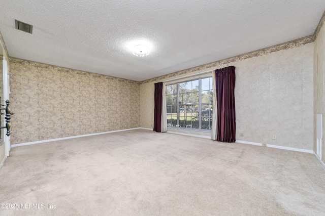 spare room with carpet, baseboards, visible vents, wallpapered walls, and a textured ceiling