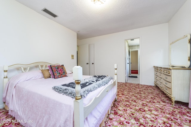 bedroom featuring visible vents, light colored carpet, a textured ceiling, and baseboards