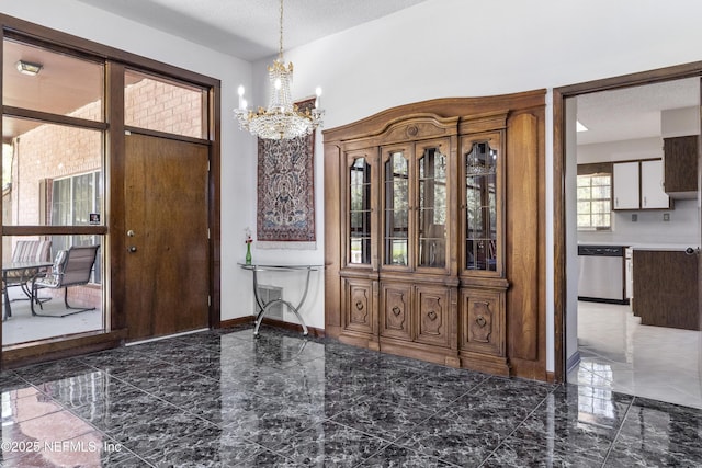 entryway featuring baseboards, marble finish floor, a textured ceiling, and an inviting chandelier