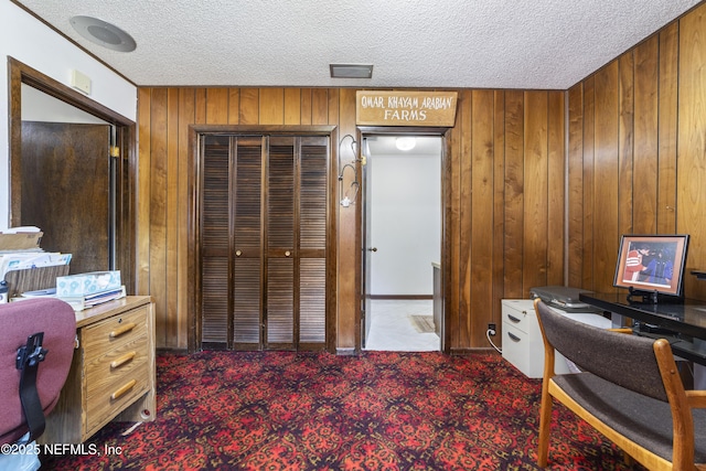 home office with carpet, wooden walls, and a textured ceiling
