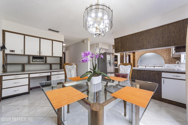 dining room with light tile patterned floors, visible vents, and a textured ceiling