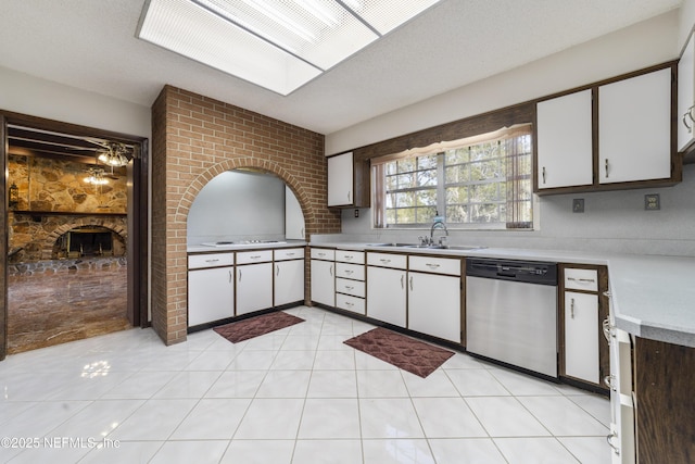 kitchen featuring white cabinetry, a fireplace, a sink, light countertops, and dishwasher