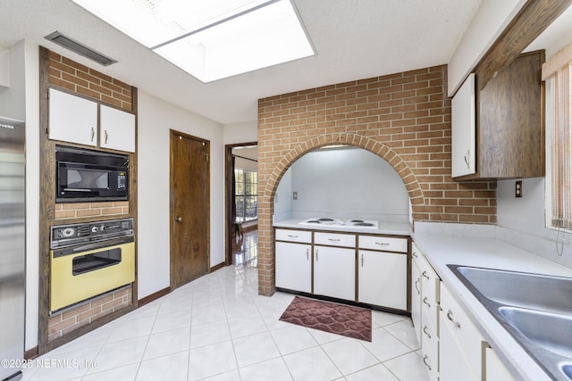 kitchen with visible vents, a sink, oven, light countertops, and black microwave