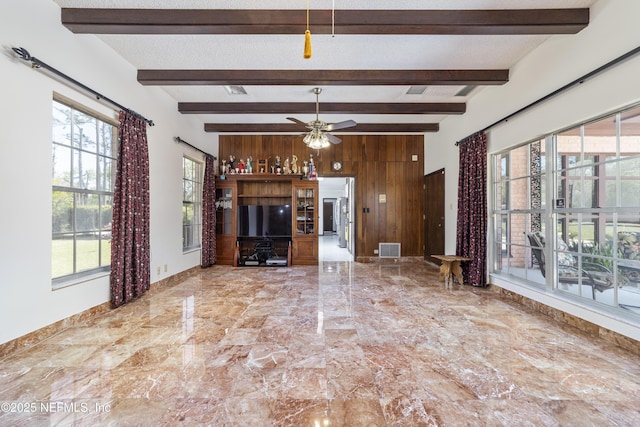 unfurnished living room featuring wooden walls, visible vents, ceiling fan, a textured ceiling, and marble finish floor