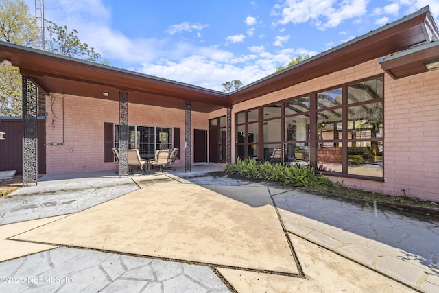 back of property with a patio and brick siding