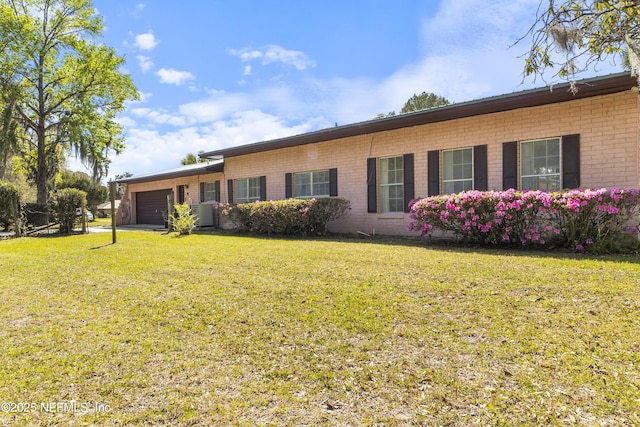 back of property with brick siding, a garage, and a lawn