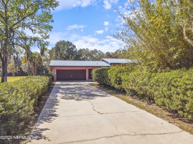 view of front facade with metal roof, a garage, and driveway