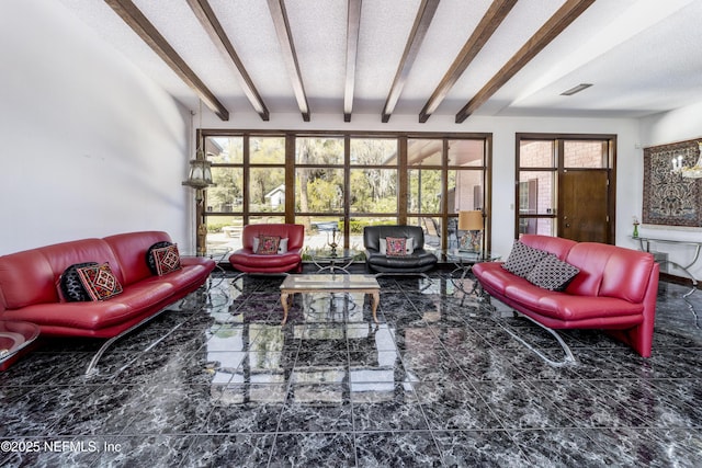 living area with beamed ceiling, plenty of natural light, a textured ceiling, and visible vents