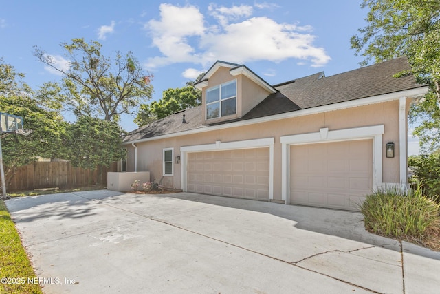 exterior space featuring stucco siding, an attached garage, fence, and concrete driveway