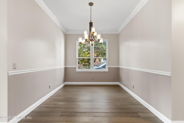 unfurnished dining area featuring an inviting chandelier, ornamental molding, baseboards, and wood finished floors