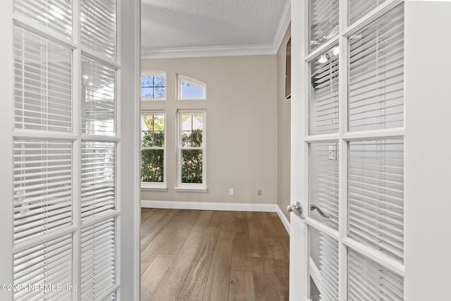 hallway with crown molding, baseboards, dark wood-type flooring, and a textured ceiling