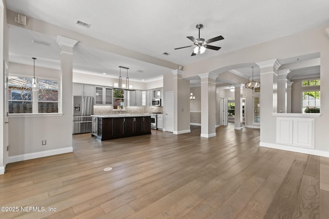 unfurnished living room with light wood finished floors, decorative columns, visible vents, and ceiling fan