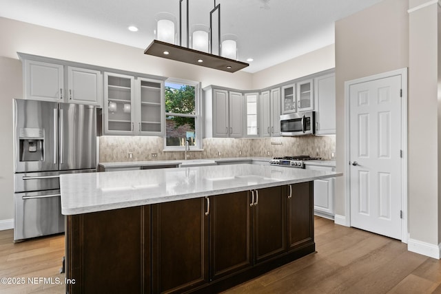 kitchen featuring decorative backsplash, light wood-style flooring, a sink, and appliances with stainless steel finishes