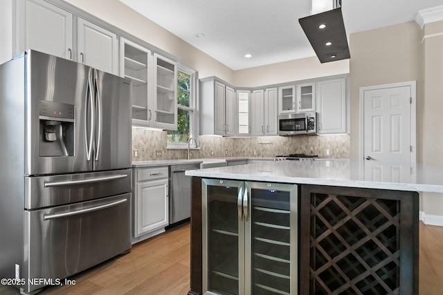 kitchen with glass insert cabinets, a sink, backsplash, and appliances with stainless steel finishes