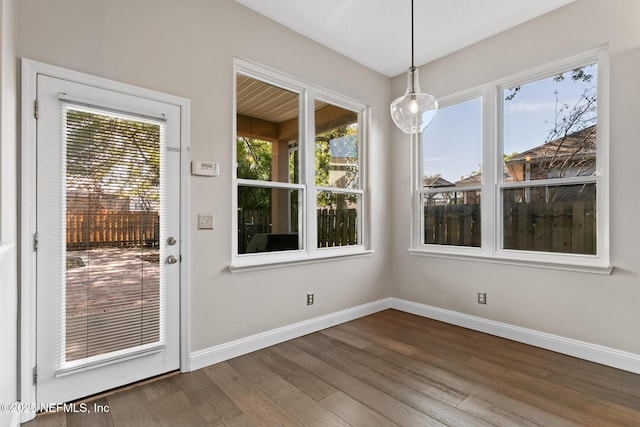 unfurnished dining area with a wealth of natural light, baseboards, and wood finished floors